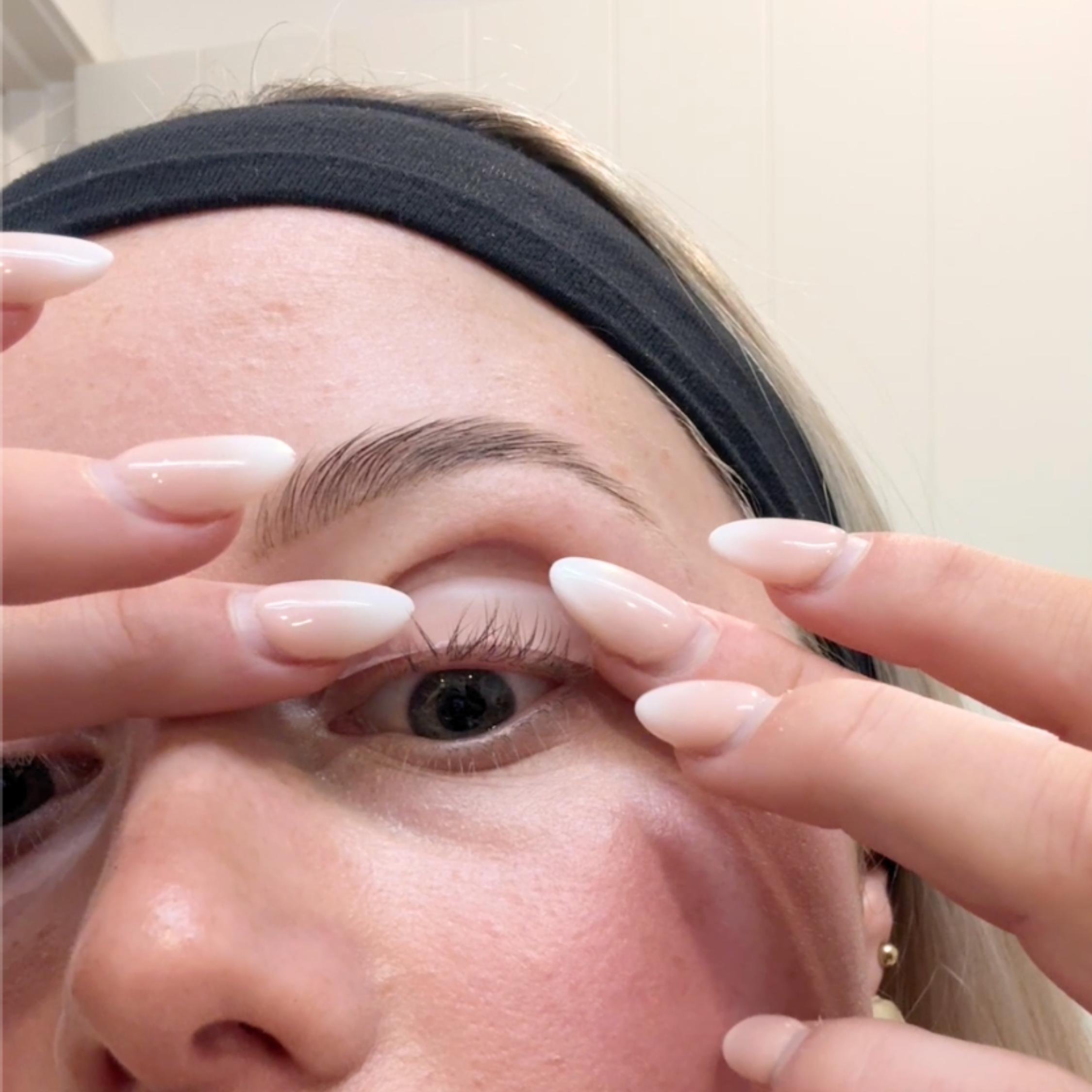 Person applying a silicon pad to eyelid for an eyelash lift at home