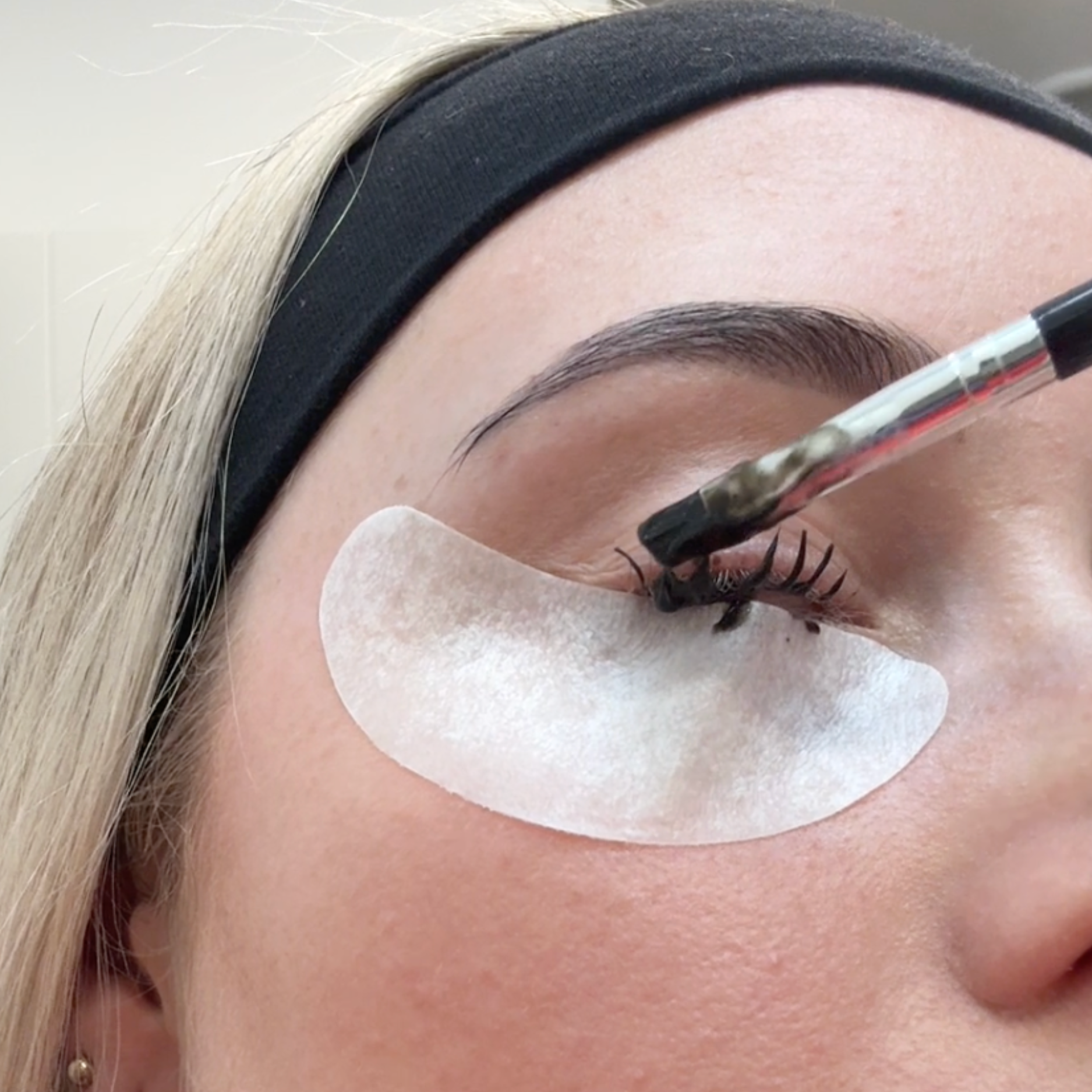 Person applying tint to eyelashes wearing an eye pad 