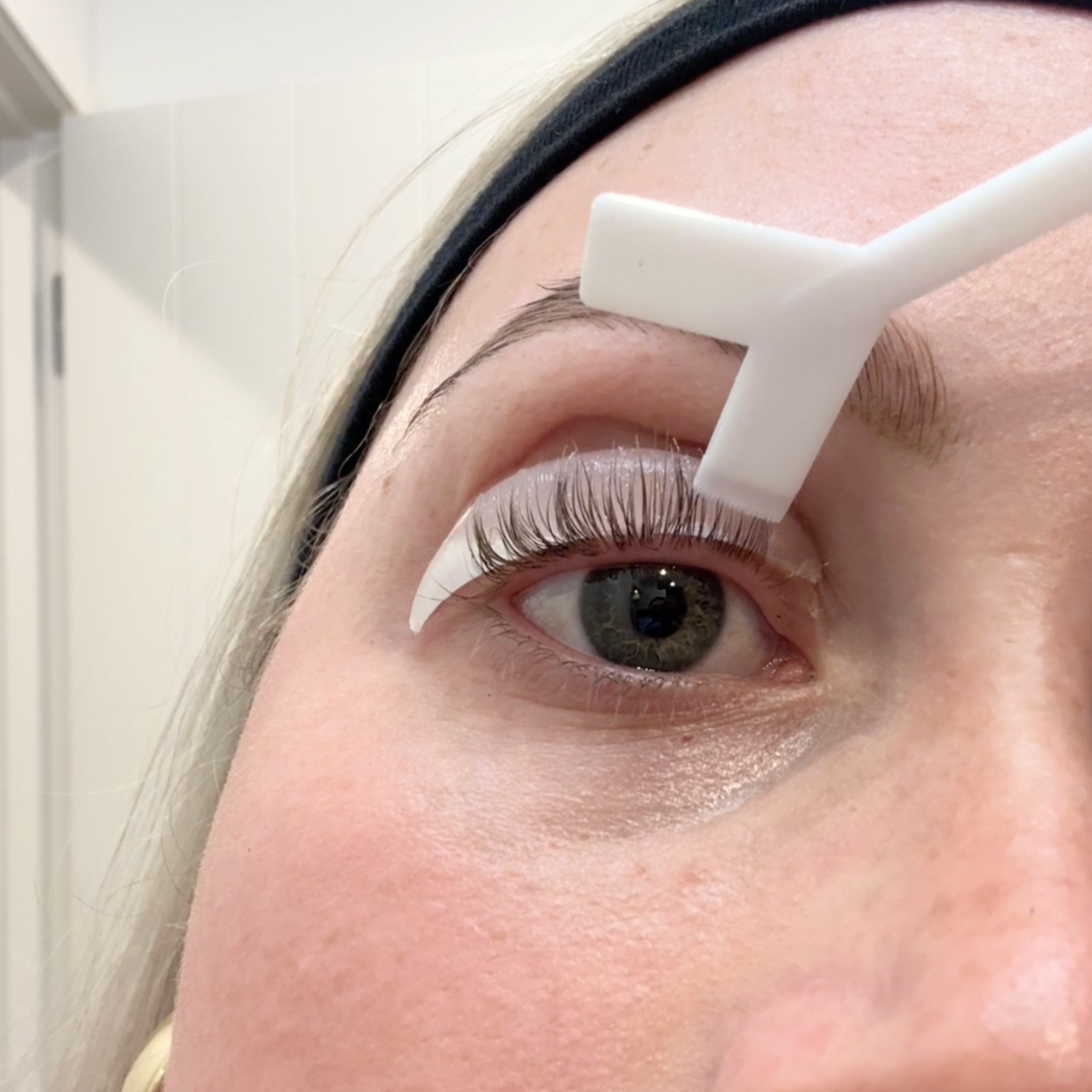 Person using a Y-brush to stick lashes on a silicon pad for a eyelash lift 