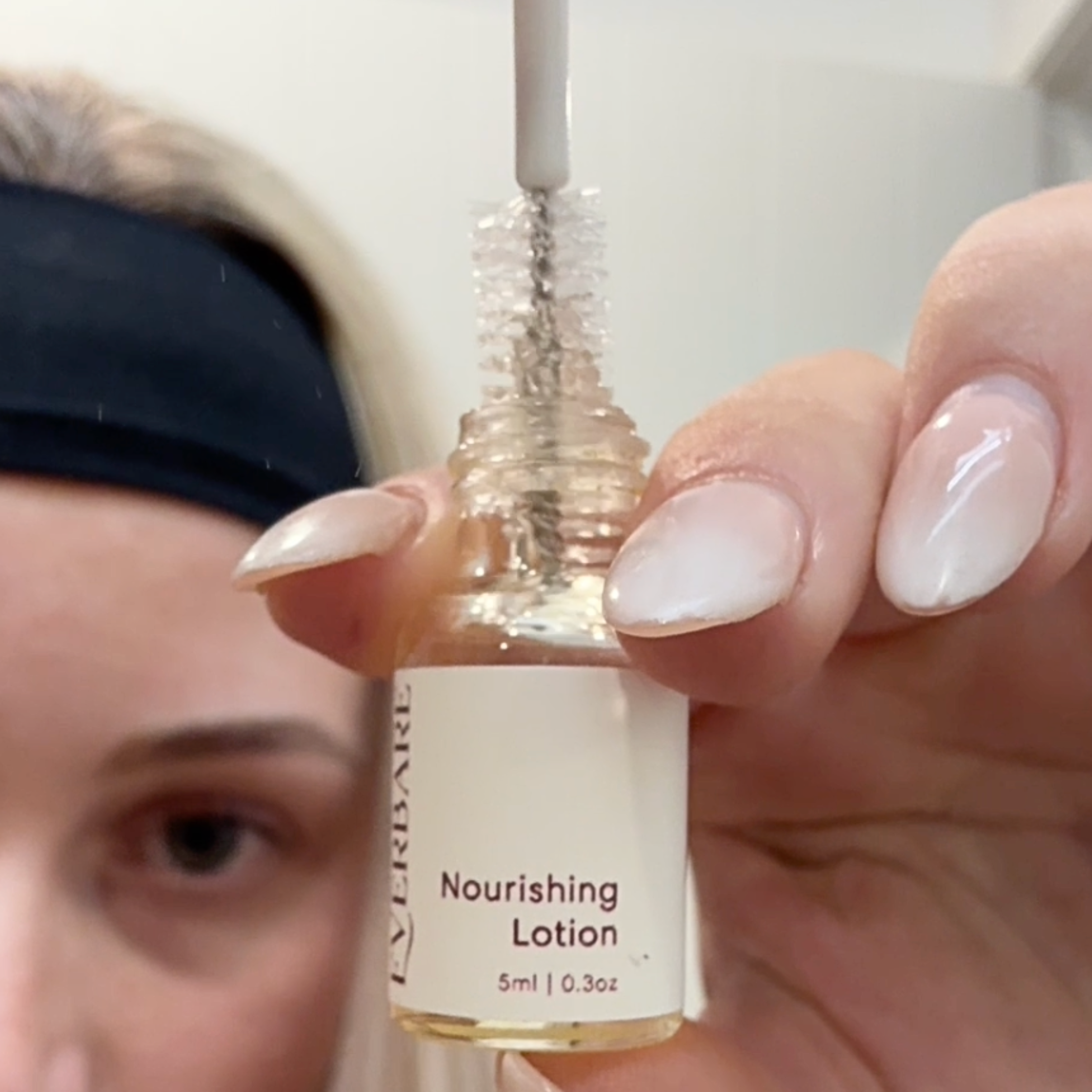 Hand holding a bottle of 'Nourishing Lotion' with a close-up of the label.